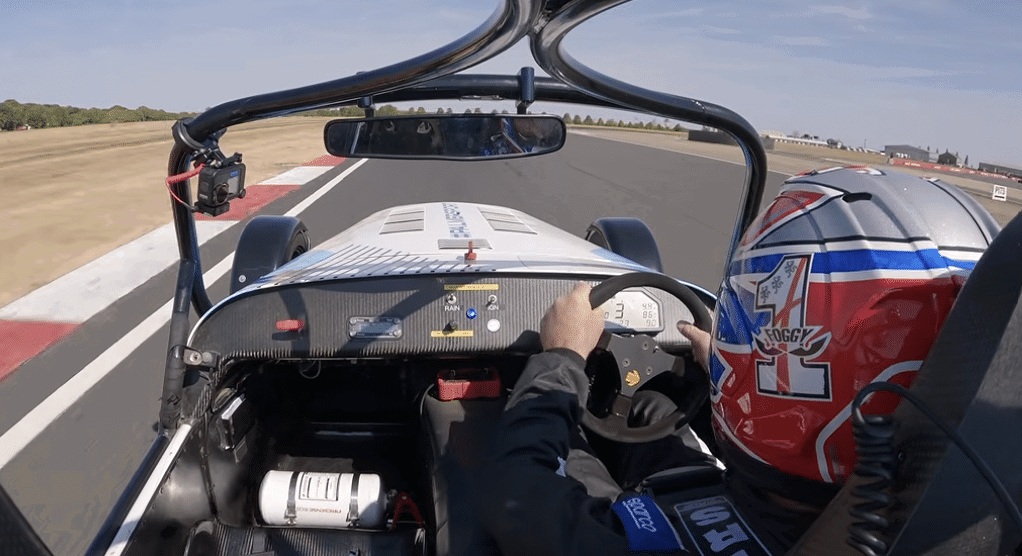 Carl Fogarty driving an open-top Caterham. 